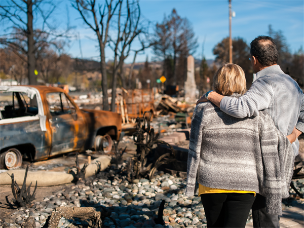 Image of couple looking at burned home